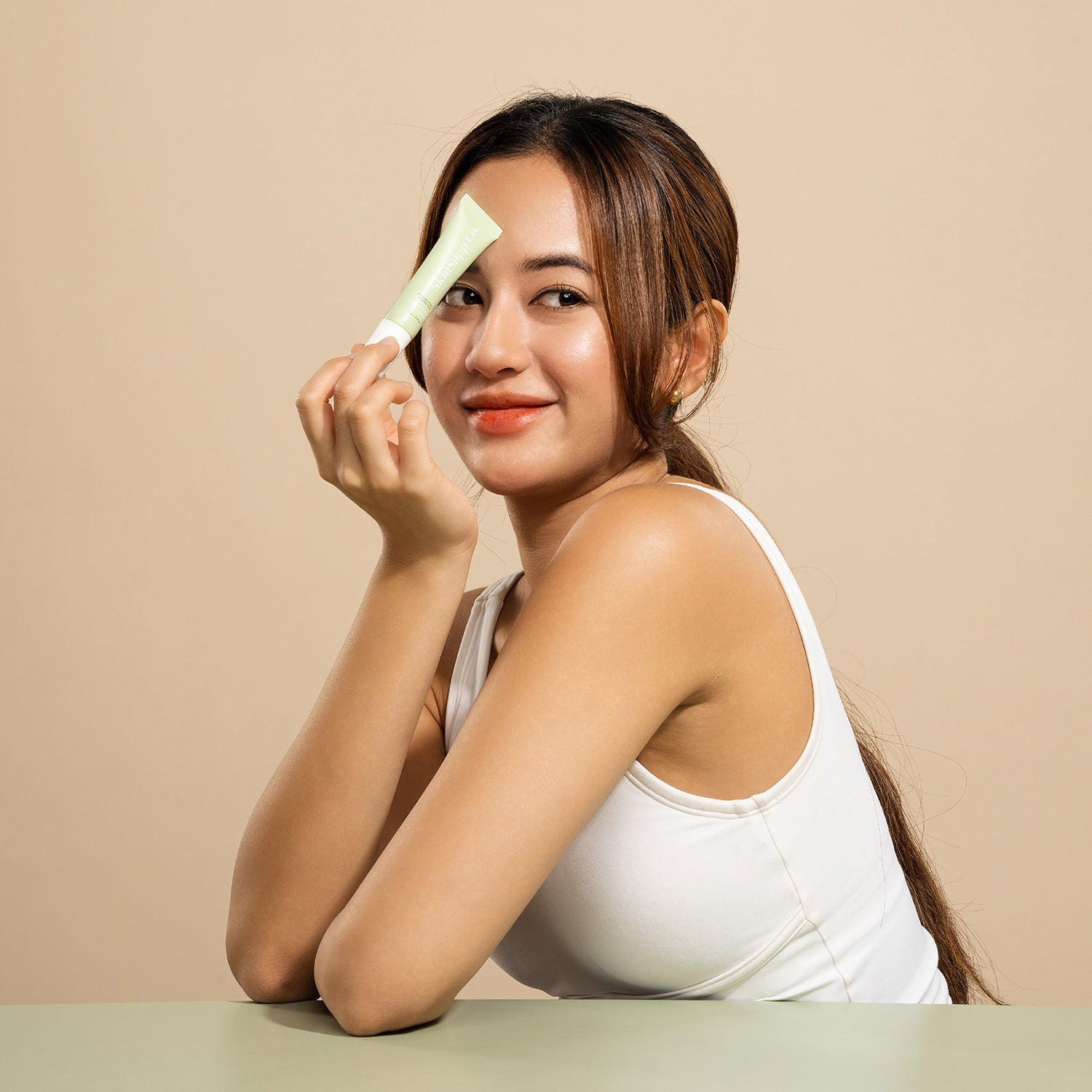 Brown haired model holding a green tube of SkinSupp Co. Intensive Acne Relief Serum